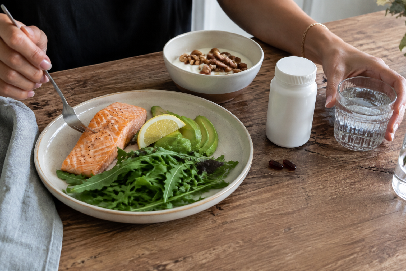 Realistic salmon, avocado, yogurt, water, and an unbranded supplement container showing a meal-based CoQ10 routine