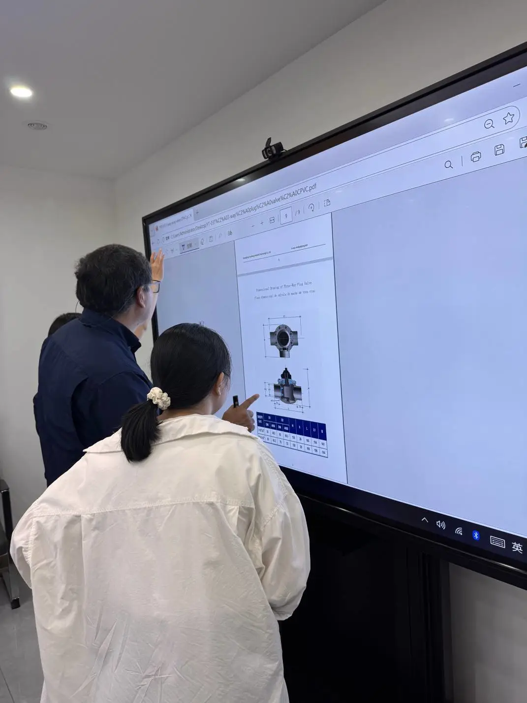 Customer and Yuantong representative review a PVC three-way ball valve technical drawing