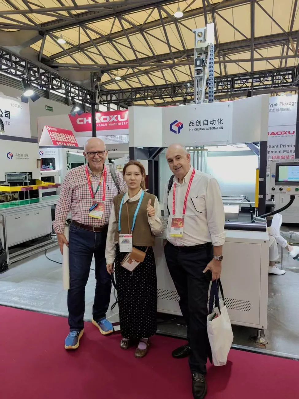 Overseas visitors with Pinchuang staff in front of the booth sign at E5C335