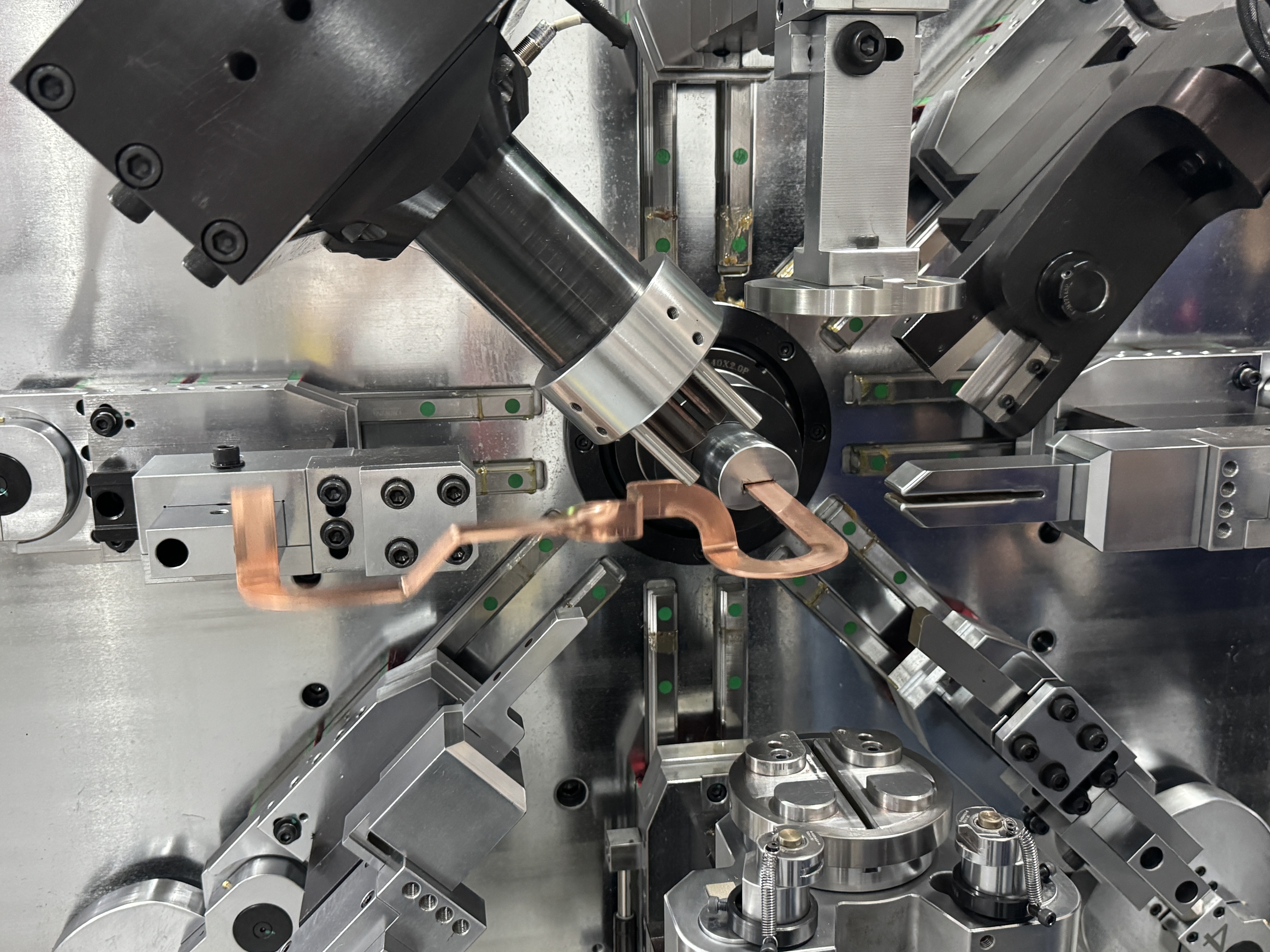 Bare flat copper busbar held in the bending head of a BELAN busbar bending machine