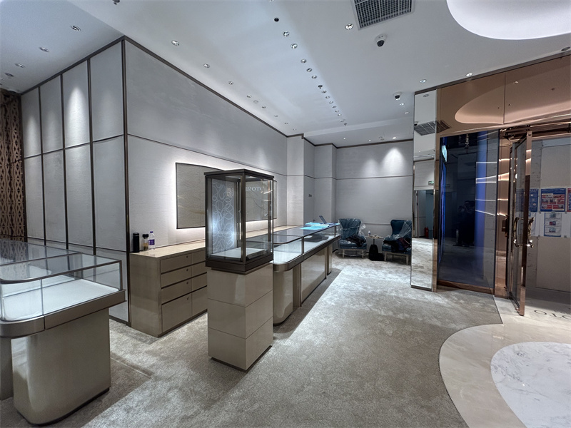 Curved glass showcases with metallic trims and illuminated display surfaces provide clear visibility across the jewelry collection.