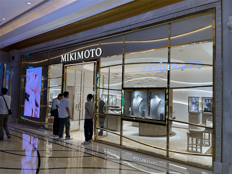 The transparent storefront provides a direct view of the illuminated jewelry displays and interior feature wall while maintaining a polished luxury presentation.