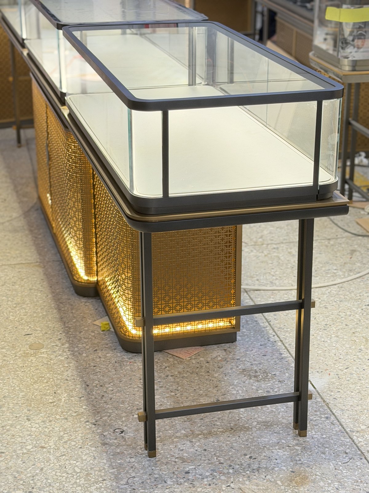 Glass top panels and exposed polished edges of a jewelry island showcase