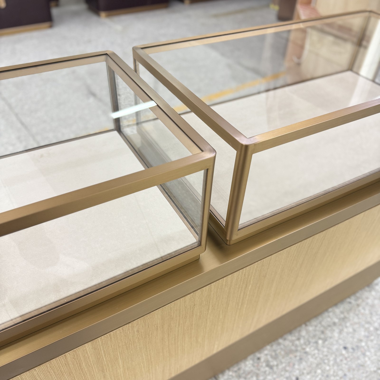 Close-up of glass display tops with gold-toned metal frames and adjoining panels on a cabinet base
